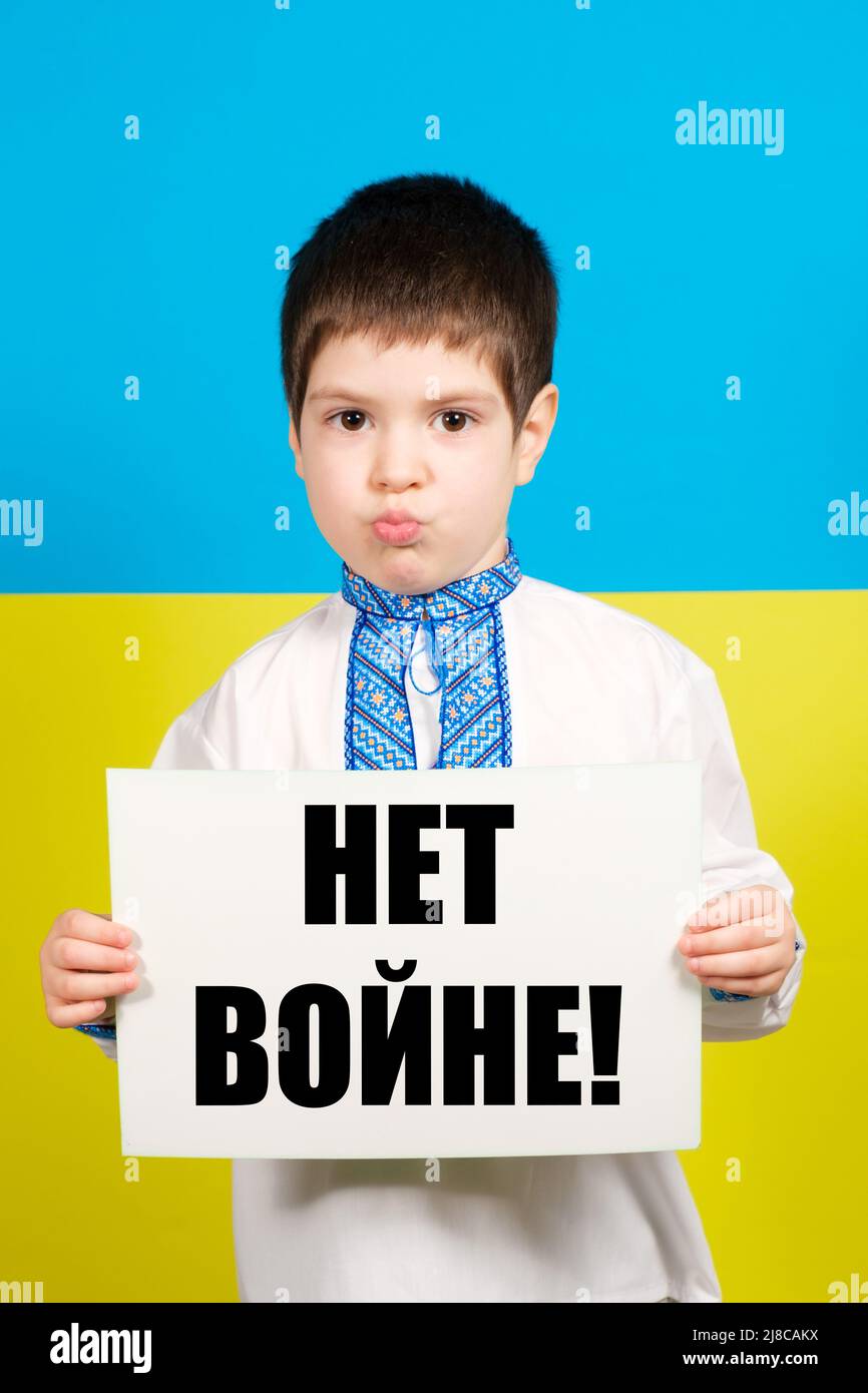 A Ukrainian child in national vyshyvanka clothes holds a sheet with a