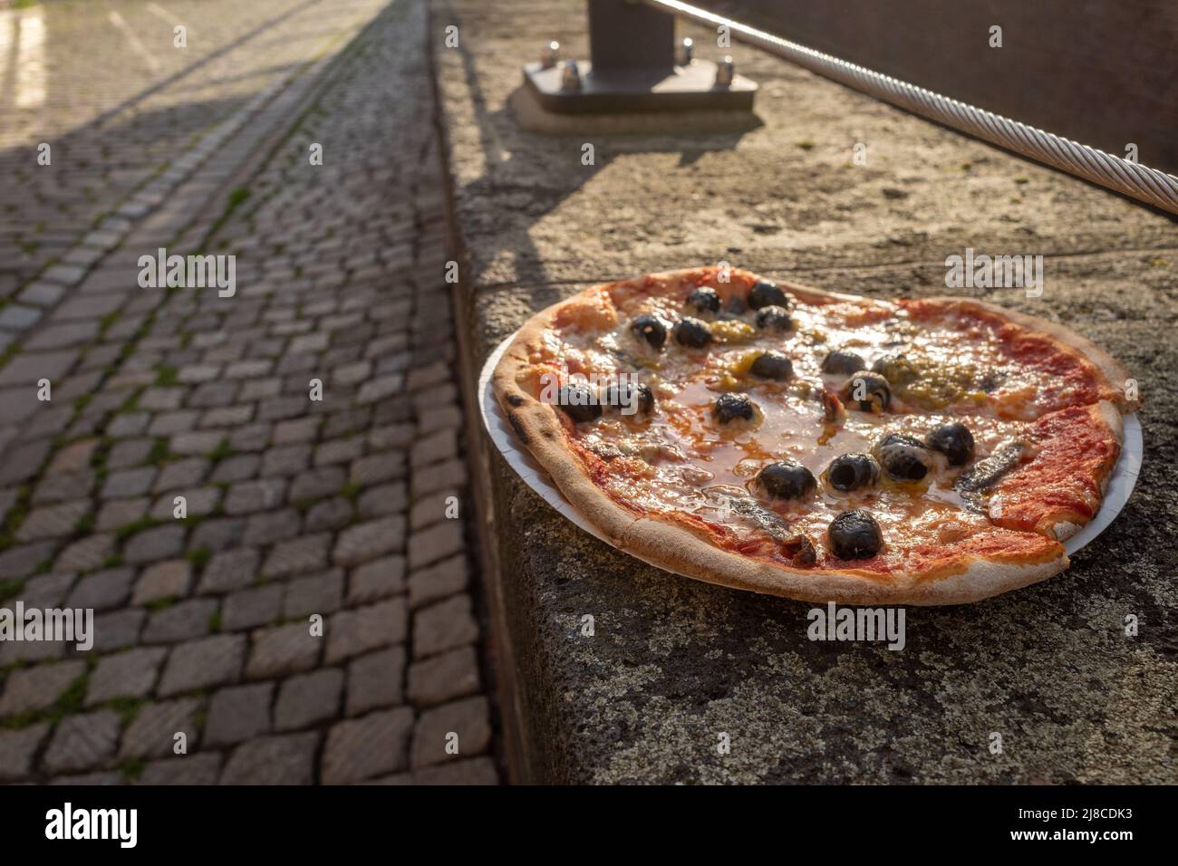 Pizza napoli style with olive and anchovy fish leave on stone fence ...