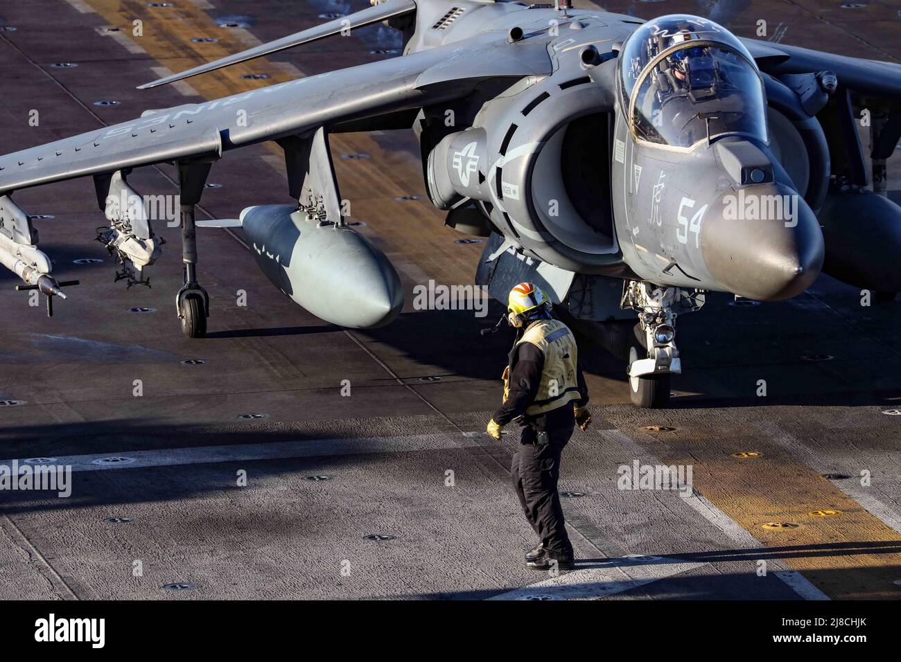 A U.S. Navy sailor prepares a Marine Corps AV-8B Harrier attached to the Tigers of Marine Attack Squadron 542, to launch from the flight deck of the Wasp-class amphibious assault ship USS Bataan, November 3, 2019 on the Atlantic Ocean. Stock Photo
