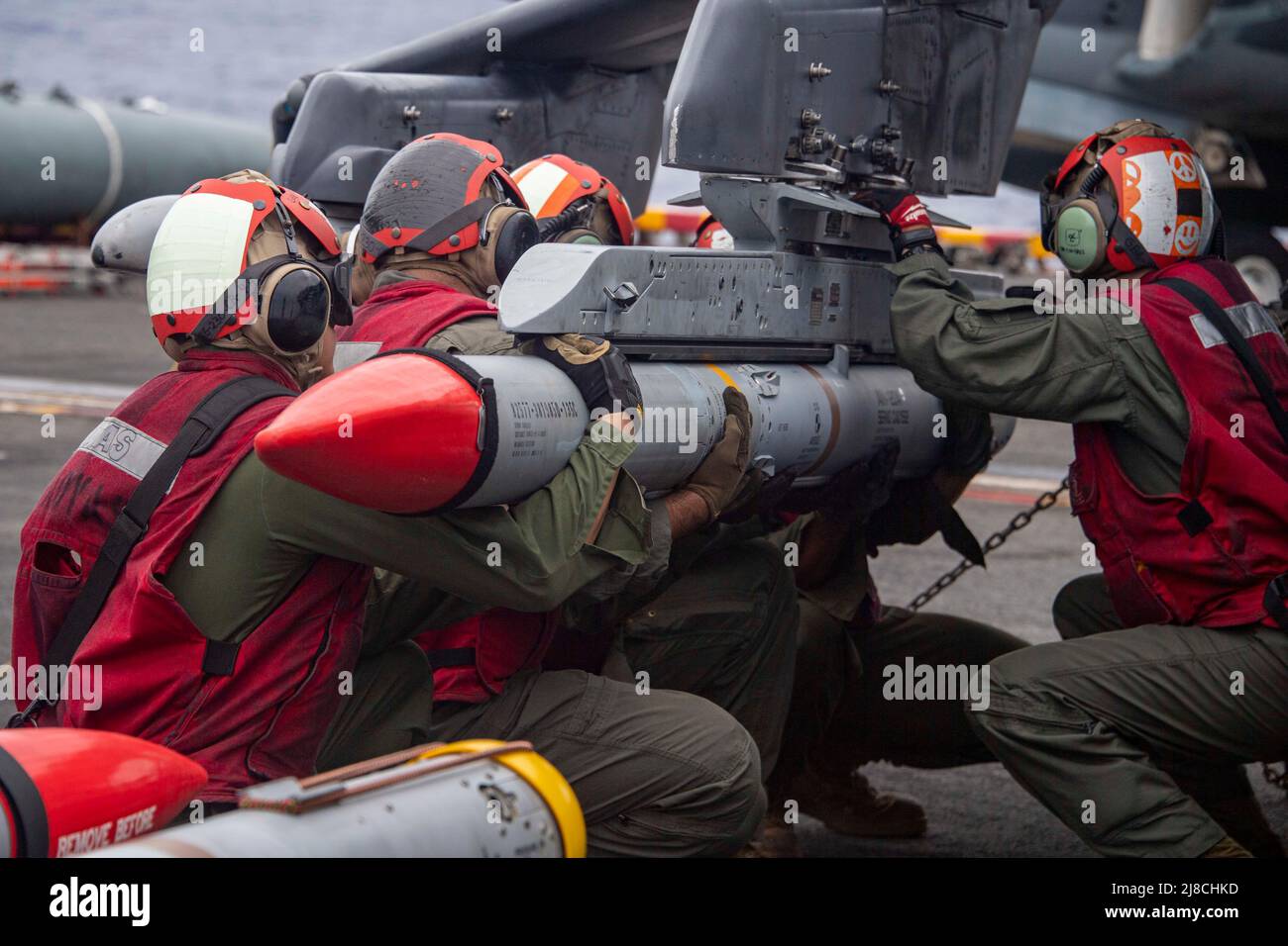 U.S. Marines load an Advanced, Medium-Range, Air-to-Air Missile onto a Marine Corps AV-8B Harrier attached to the Black Sheep of Marine Attack Squadron 214, during operations on the flight deck of the Wasp-class amphibious assault ship USS Essex in support of operation Noble Fusion, February 3, 2022 operating on the Luzon Strait. Stock Photo