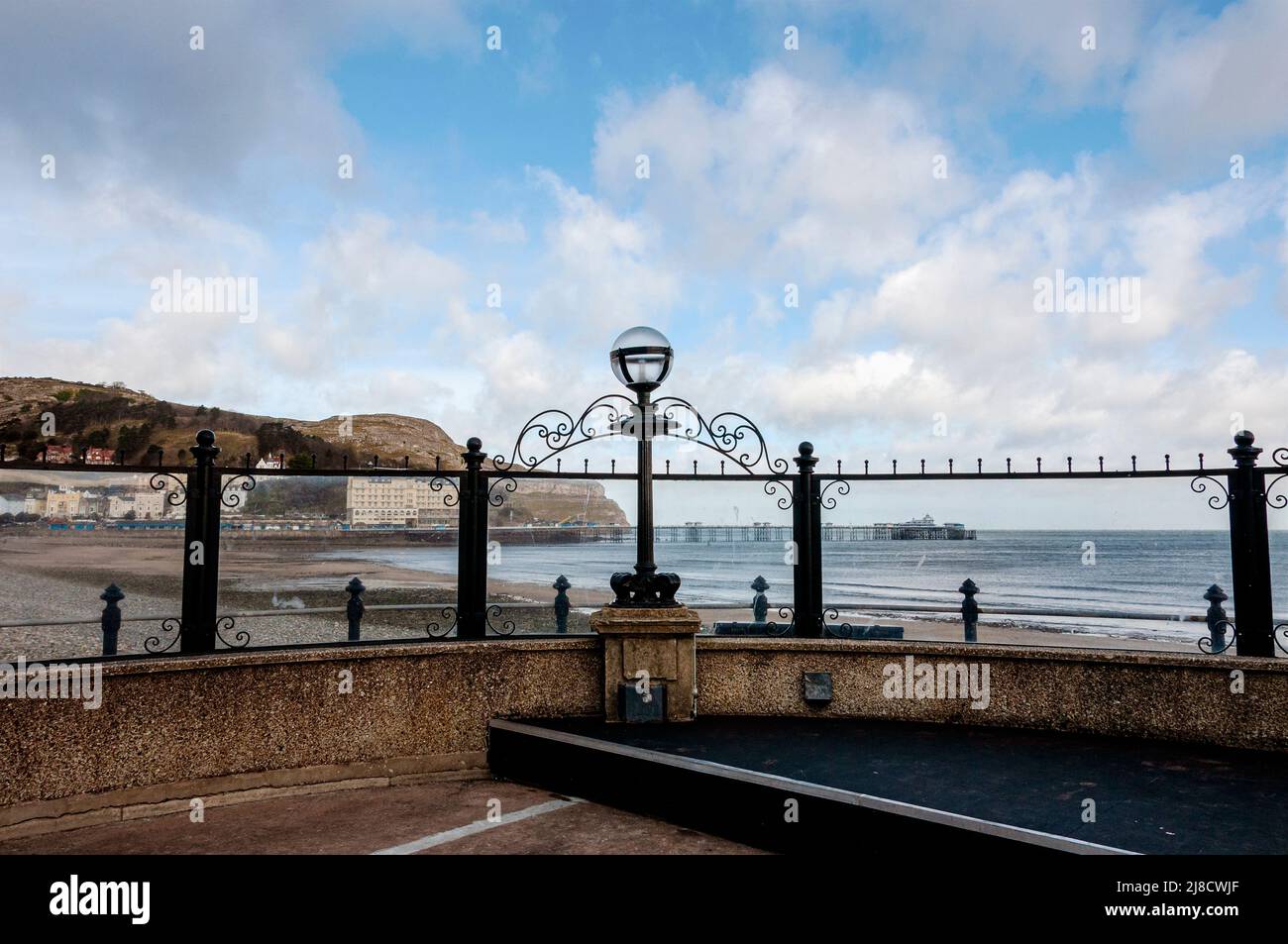 Early 20th century concrete iron and stone Llandudno bandstand with a semi circular rear wall to the podium furnished with an iron lamp on a pier Stock Photo