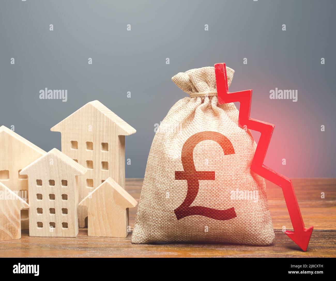 Houses and british pound sterling money bag with down arrow. Reducing maintaining cost, energy efficiency. Falling of real estate market prices. Realt Stock Photo