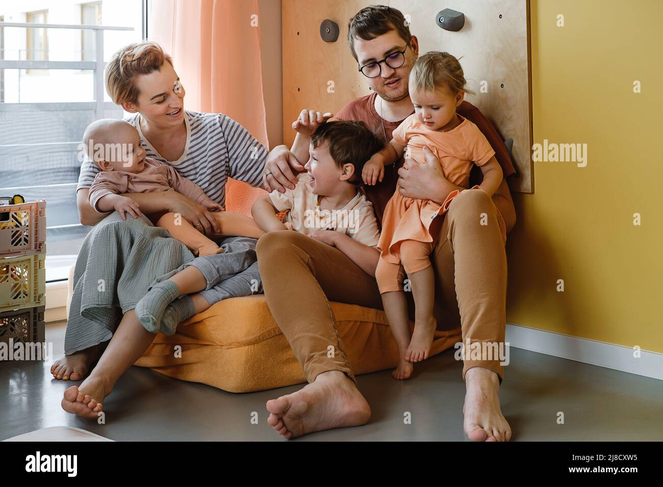 Big family in sunny play room. Parents playing with kids and toys. Happy time together with games. Mother father son daughters at modern colorful home Stock Photo