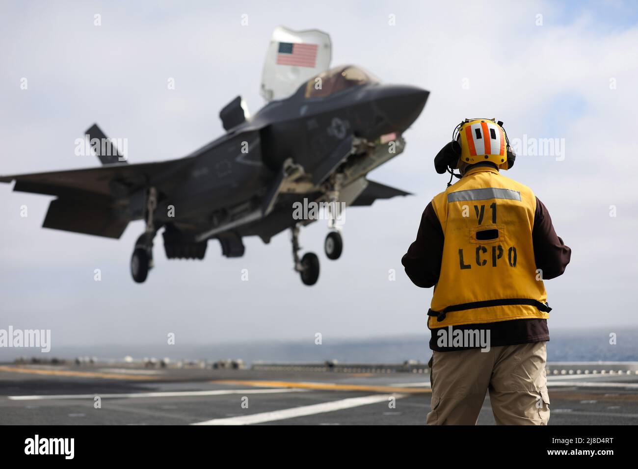 U.S. Navy Senior Chief Aviation Boatswains Mate Dennis Boyle, watches a Marine Corps F-35B Lightning II fighter aircraft, attached to the Knightriders of Marine Medium Tiltrotor Squadron 164, performs a vertical landing on the flight deck of the Wasp-class amphibious assault ship USS Makin Island, October 19, 2020 operating on the Pacific Ocean. Stock Photo