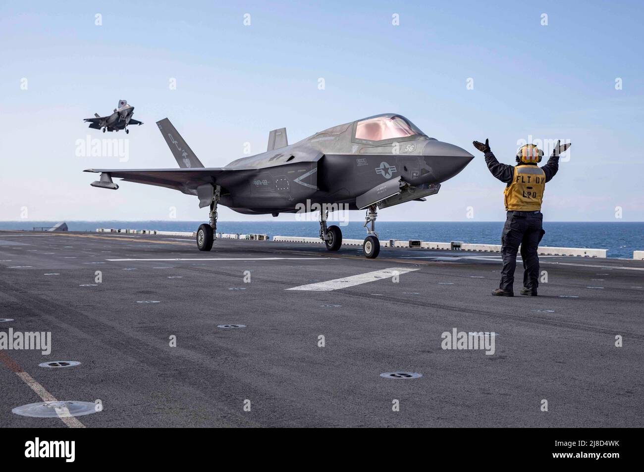 U.S. Navy Aviation Boatswains Mate 1st Class Jenna Leggett directs a U.S. Marine Corps F-35B Lightning II fighter aircraft, attached to the Knightriders of Marine Medium Tiltrotor Squadron 164, after landing on the flight deck of the Wasp-class amphibious assault ship USS Makin Island during operation Northern Edge 2021, May 5, 2021 operating on the Gulf Of Alaska. Stock Photo