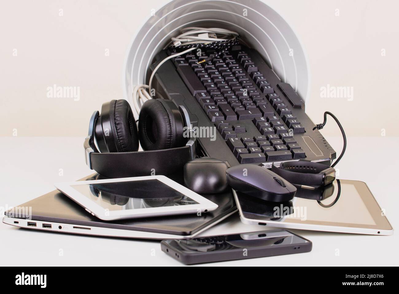 Recycling bin and old digital tablet, cell phone, headphone, cords and electronic devices