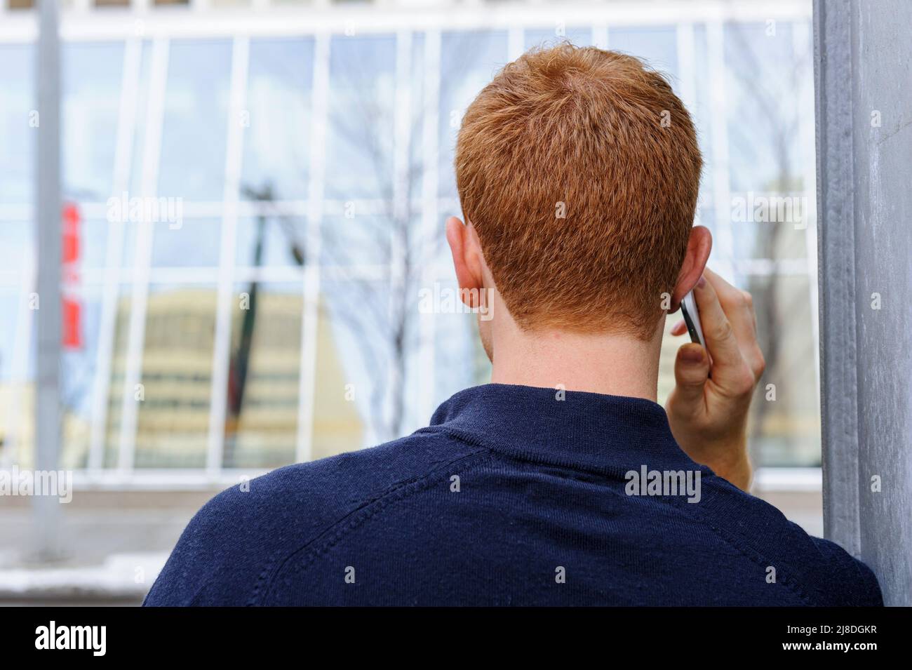 A young man with red hair using a electronic communication device mobile phone or cell phone Stock Photo