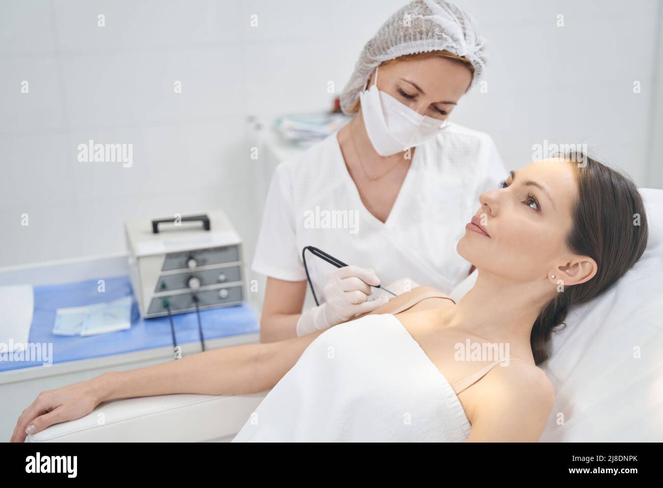 Doctor performing laser mole removal procedure in beauty clinic Stock
