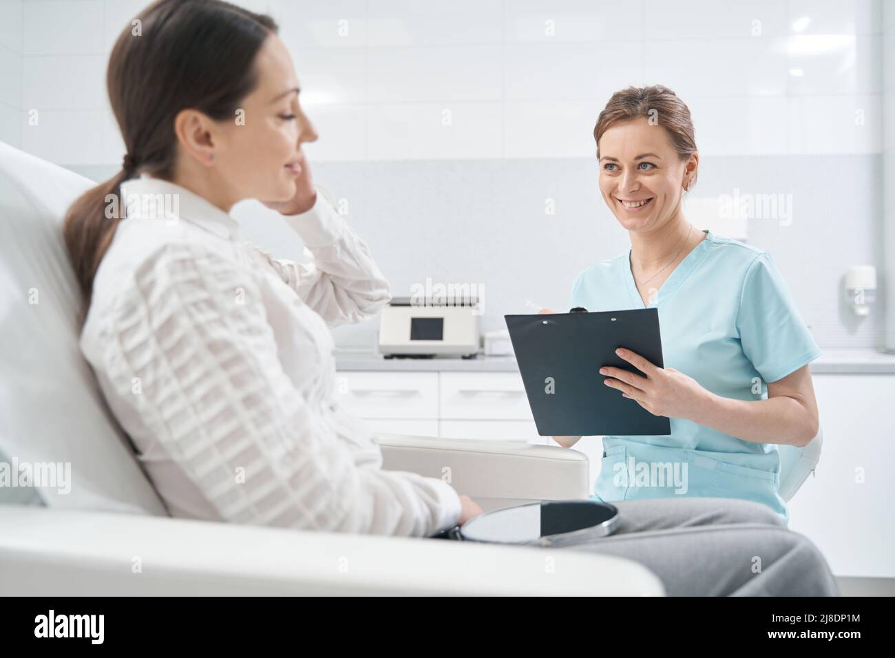 Cheerful doctor talking with woman in beauty salon Stock Photo - Alamy