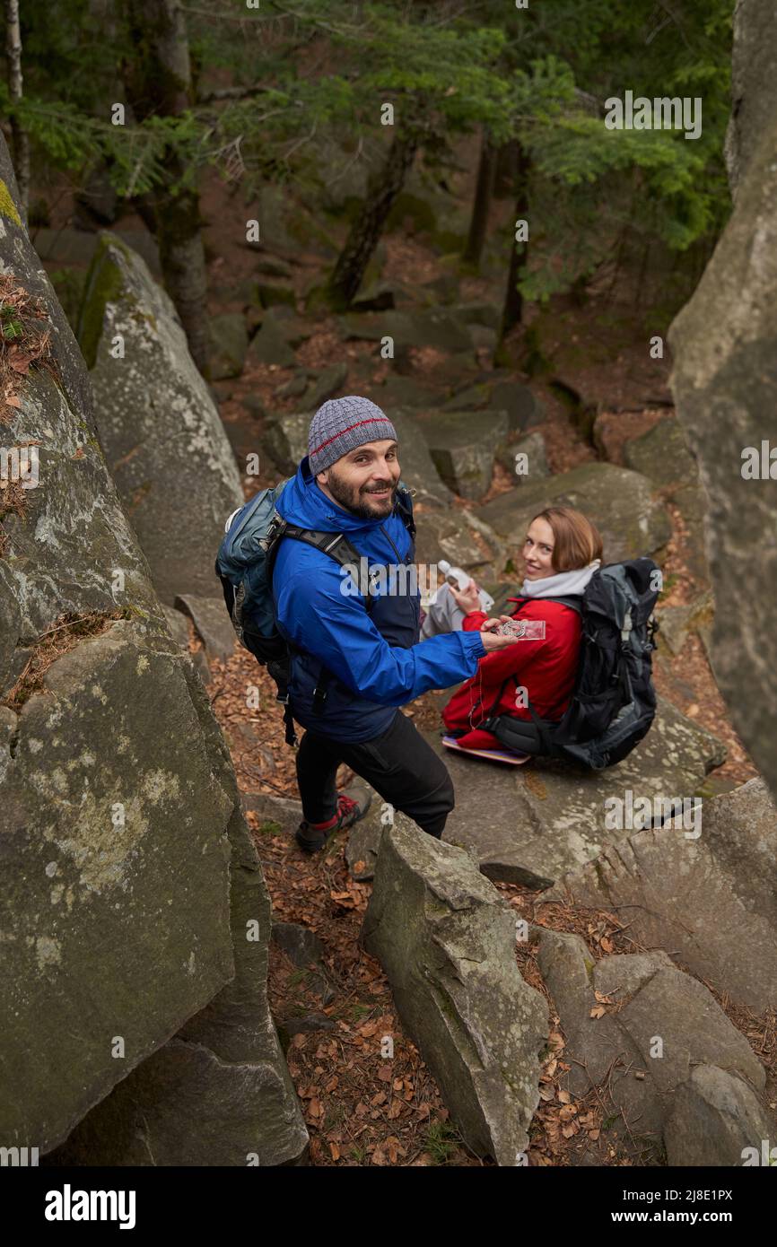 Cheerful man using compass during rest stop with woman Stock Photo