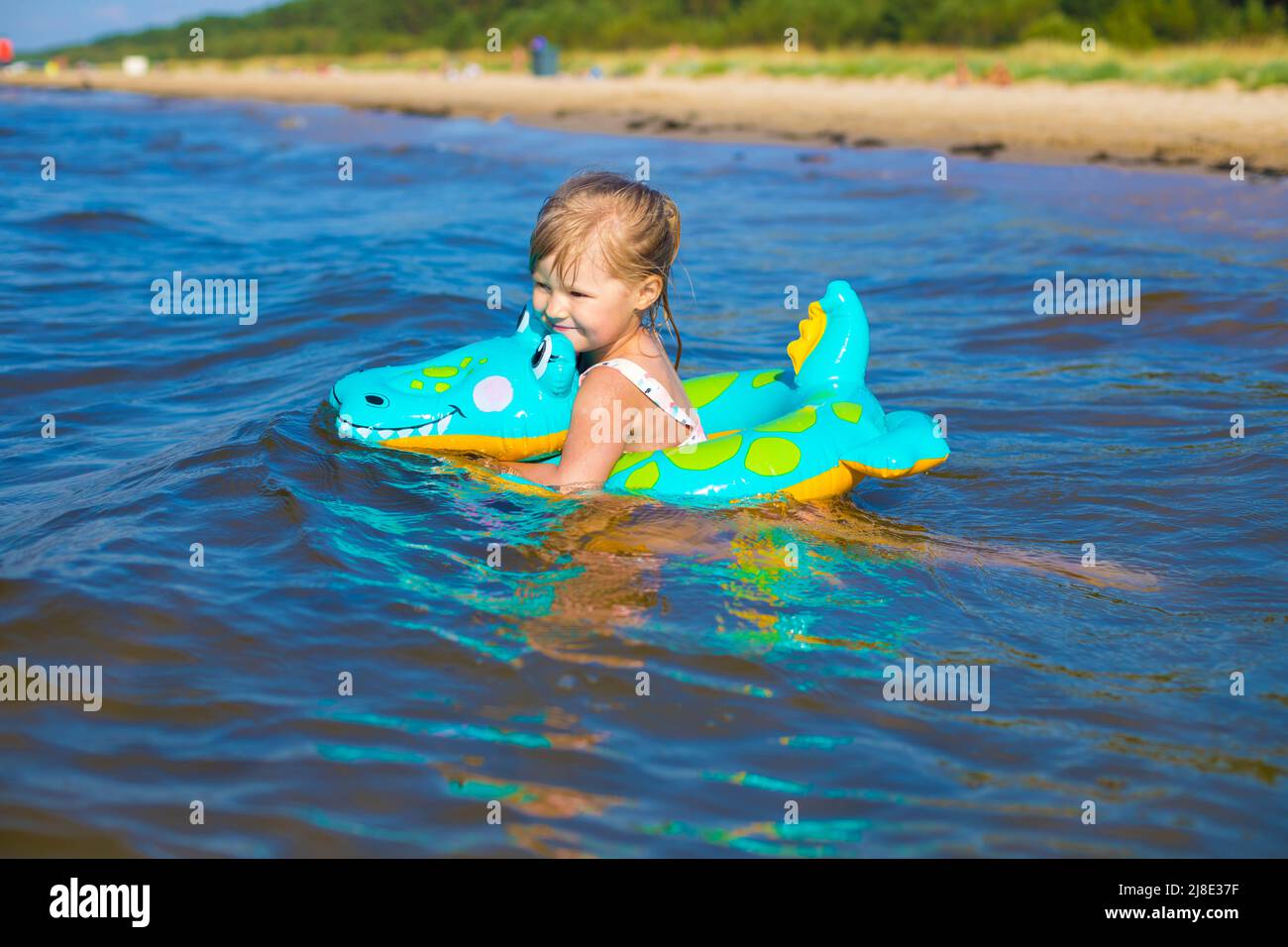 Happy girl swimming on an inflatable crocodile toy in the sea Stock