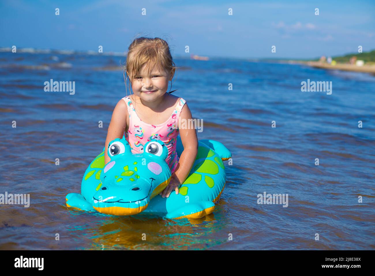 Happy girl swimming on an inflatable crocodile toy in the sea Stock