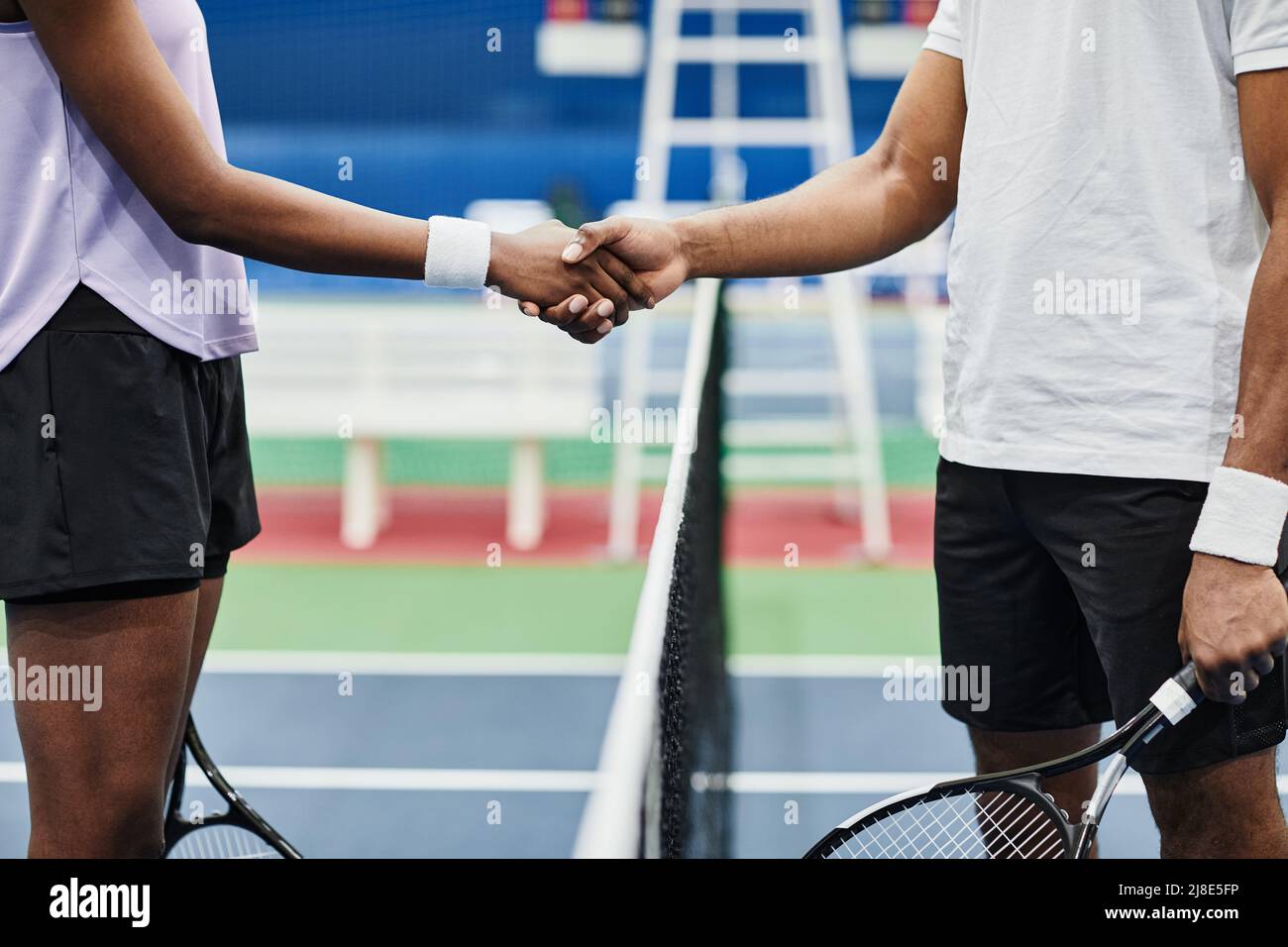 Side view closeup of two tennis players shaking hands across net during