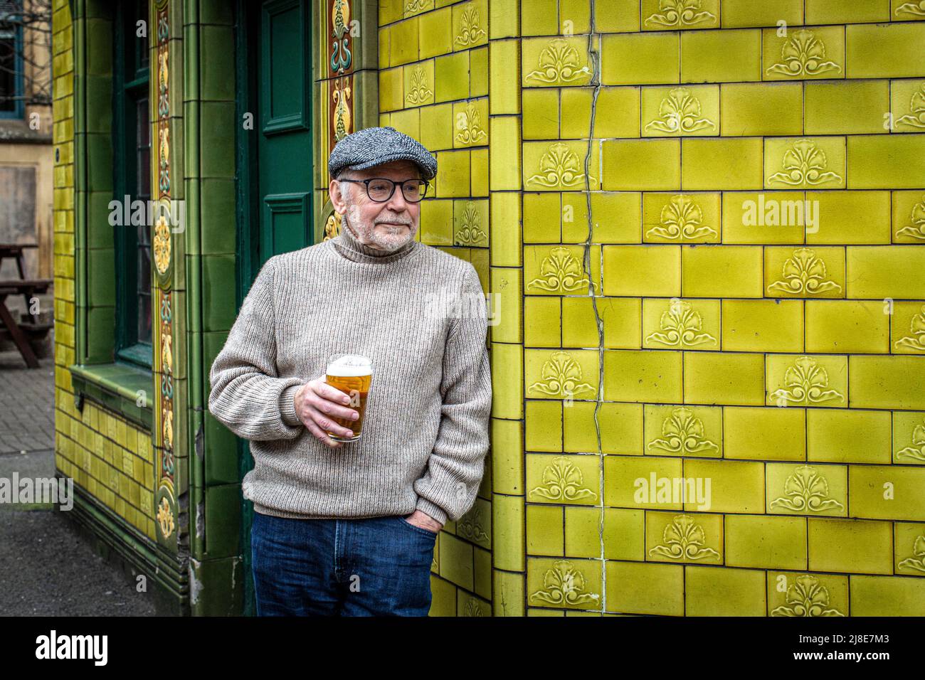 Male stand outside a pub enjoying a drink at The Peveril of the Peak traditional English city pub, located on Great Bridgewater Street, Manchester, UK Stock Photo