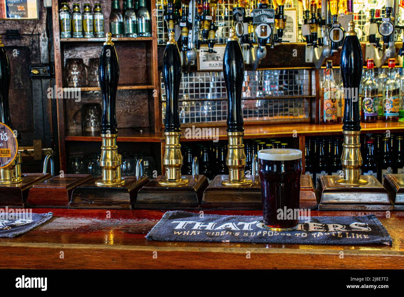 Pint glass of Spingo Ale , on beer mat with bar pumps at The Blue Anchor Inn in Helston, Cornwall , United Kingdom Stock Photo