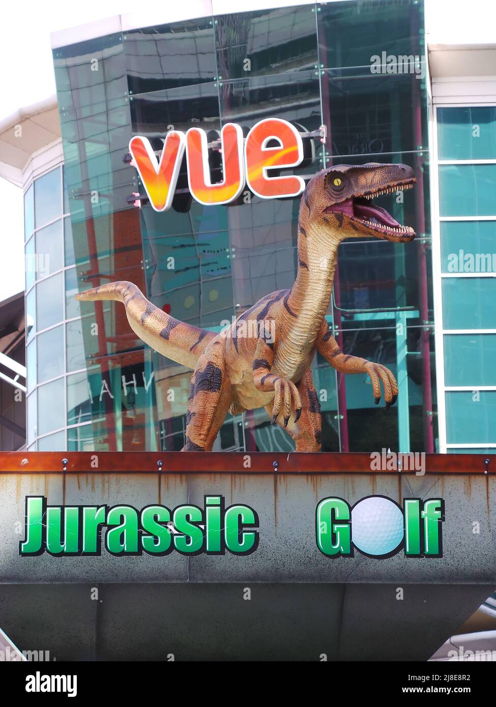 Reading, United Kingdom - April 11 2014:  The entrance to the Jurassic crazy golf course, topped by a model velociraptor, outside Vue Cinema on Rivers Stock Photo