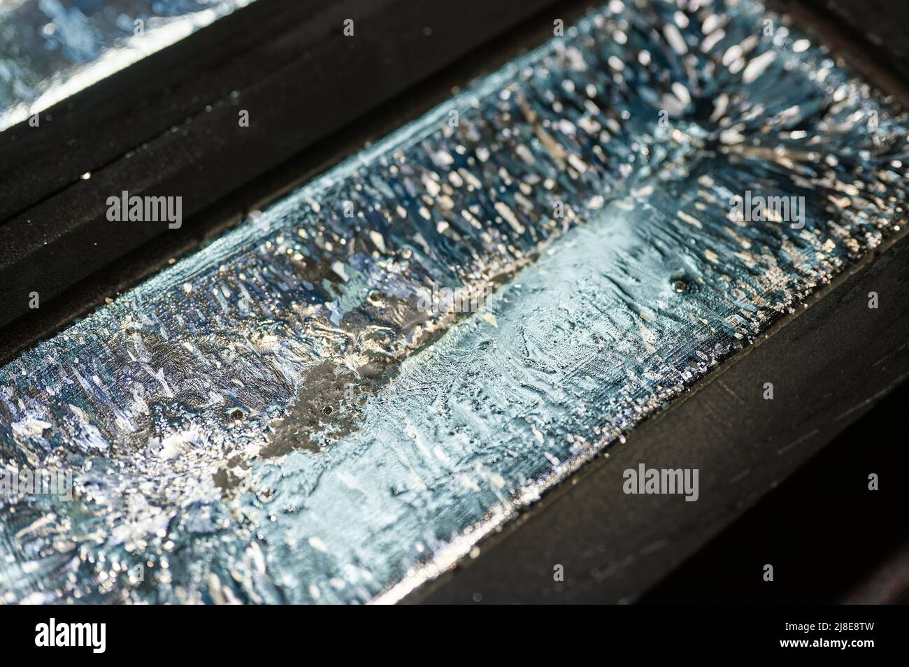 Biscuit of shiny silver cools down in graphite casting form Stock Photo