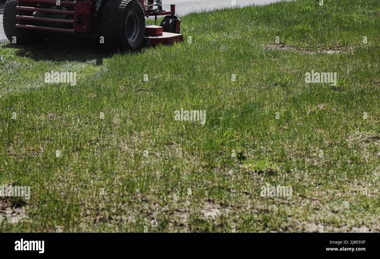 Ride-on lawnmower cutting grass along the street. mowing garden care work tool Stock Photo