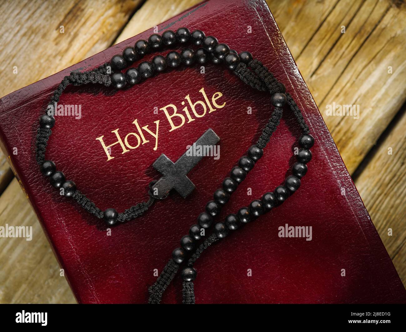 Holy bible book and catholic cross on wooden background. Solar lighting. Low angle view. There are no people in the photo. Religion, Christianity, Cat Stock Photo