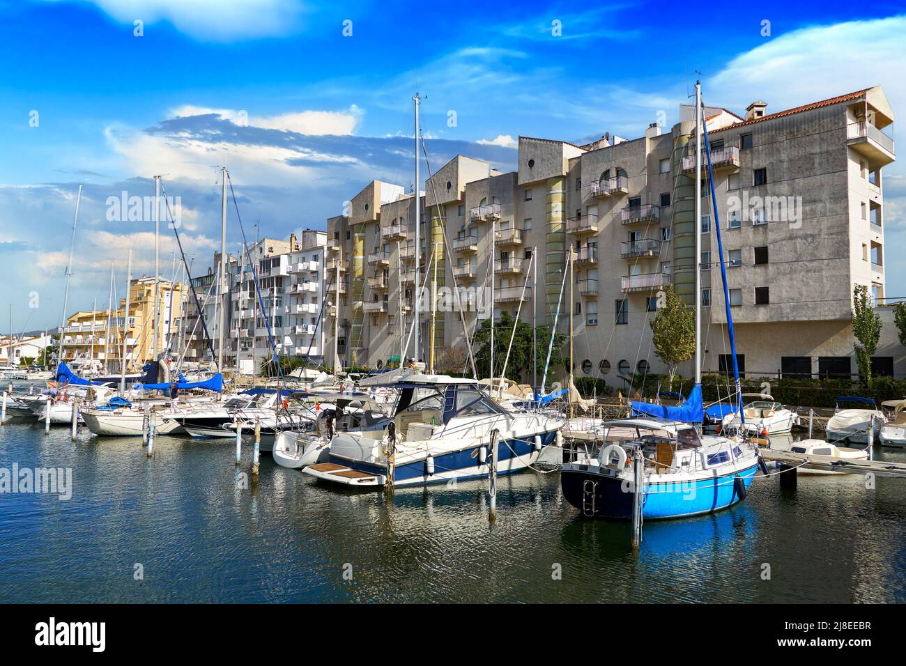 Beautiful view of the pier with boats, yachts and a high-rise building on the shores of the picturesque Mediterranean canal in the Golf de Roses again Stock Photo