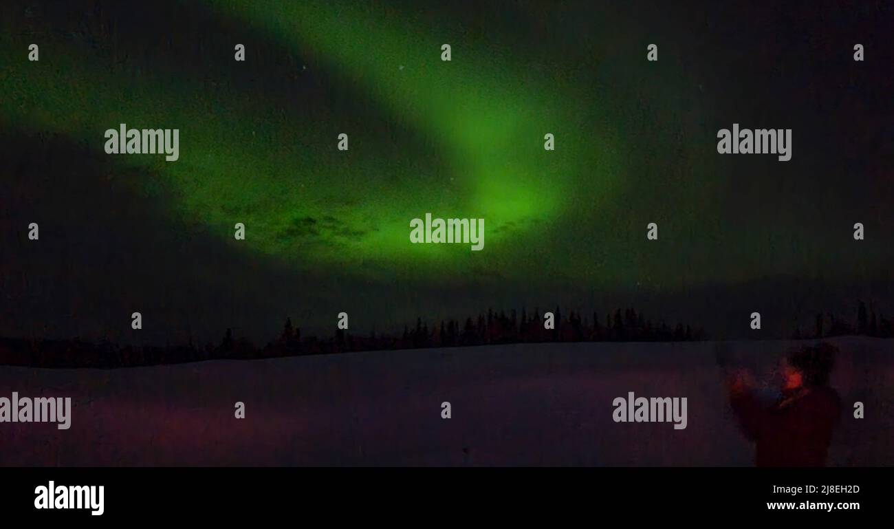 Woman photographs Northern Lights at Aurora Pointe outside Fairbanks. Stock Photo