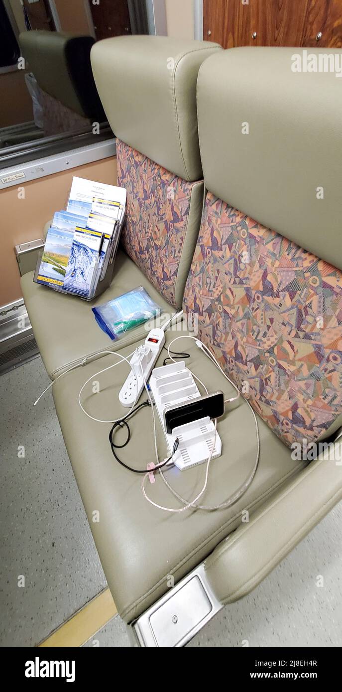 Charging station for phones, tablets and laptops, set up on a seat for passengers riding on Alaska Railroad train. Stock Photo