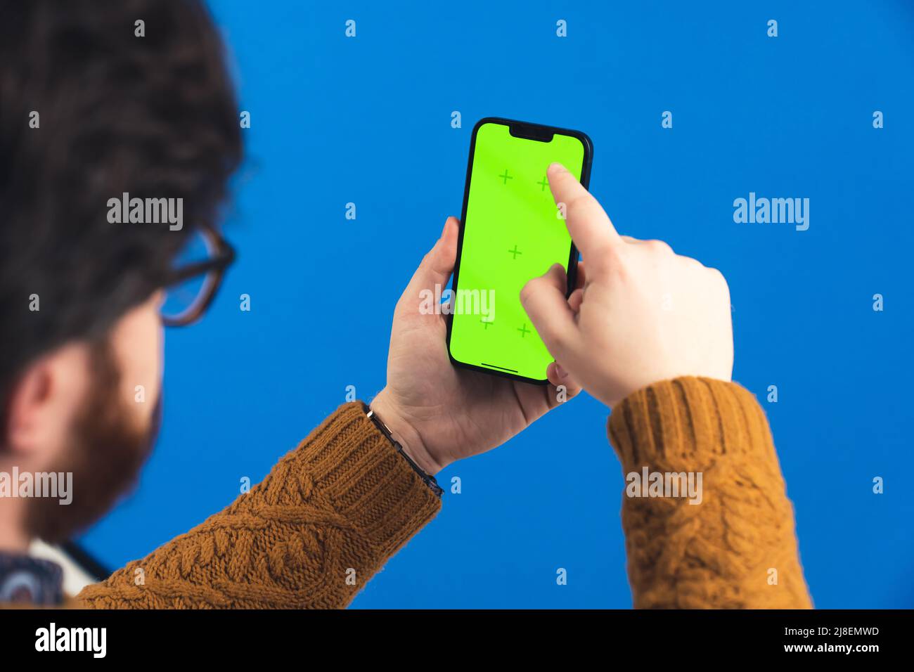 Studio close up shot of a middle-aged man in a jumper scrolling on his smartphone. Chroma key screen, isolated. High quality photo Stock Photo