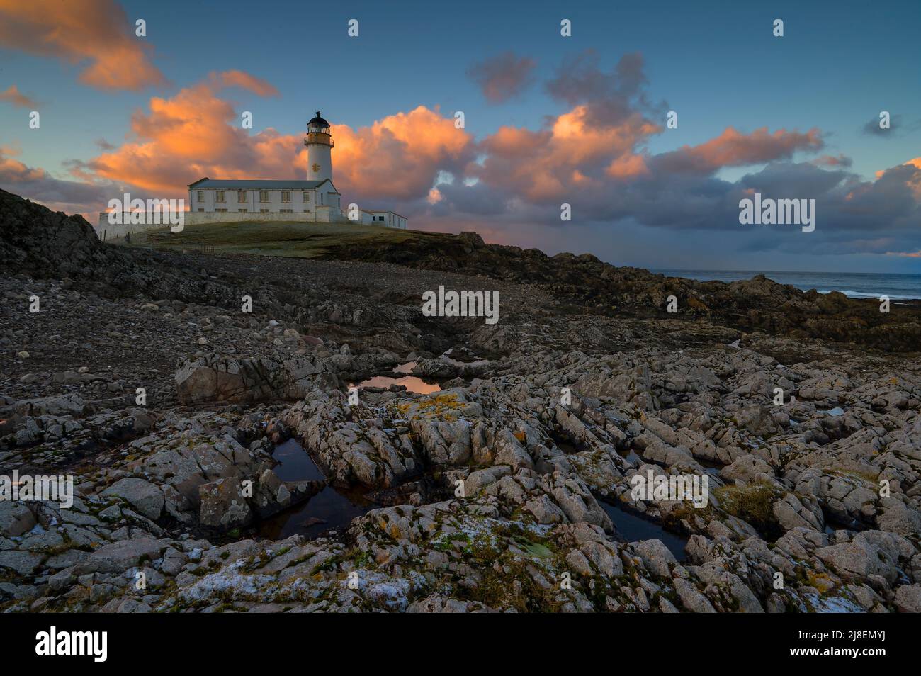 The South lighthouse against a sky illuminated by a sunrise, Fair Isle Stock Photo