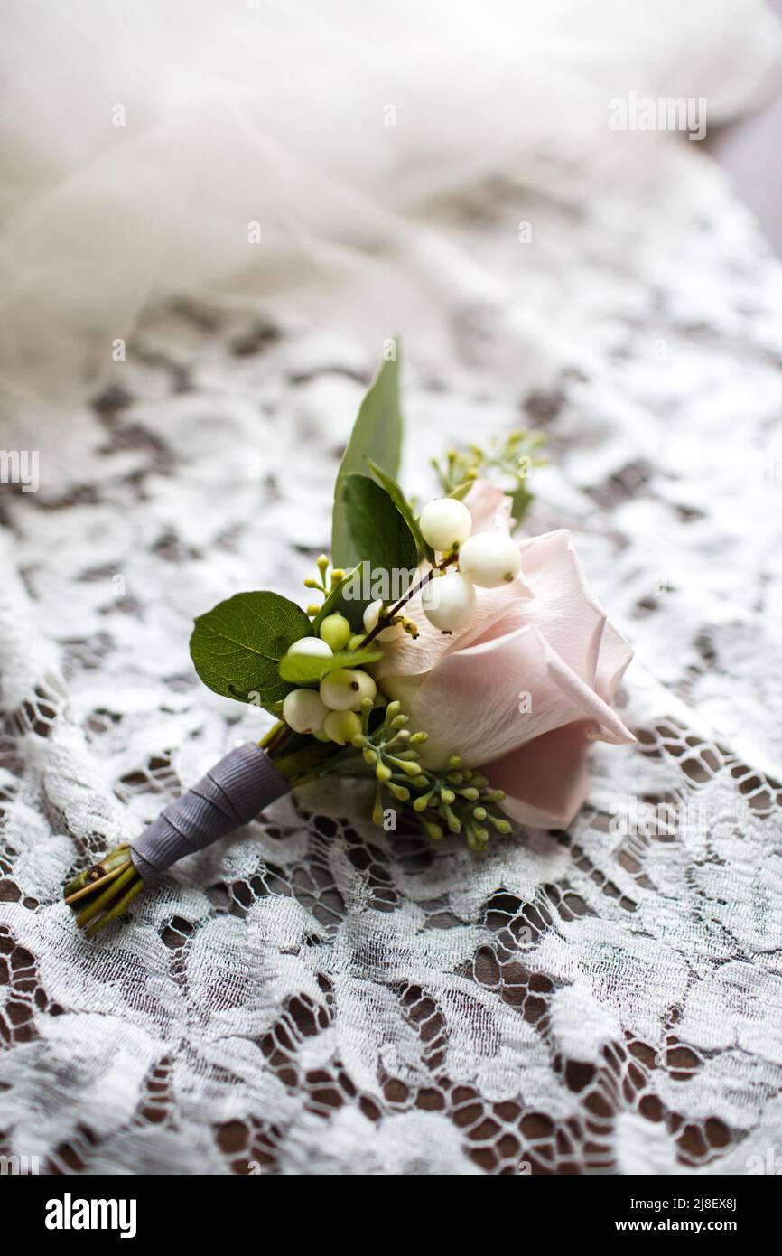 Wedding boutonniere lies on a beige lace dress. Stock Photo