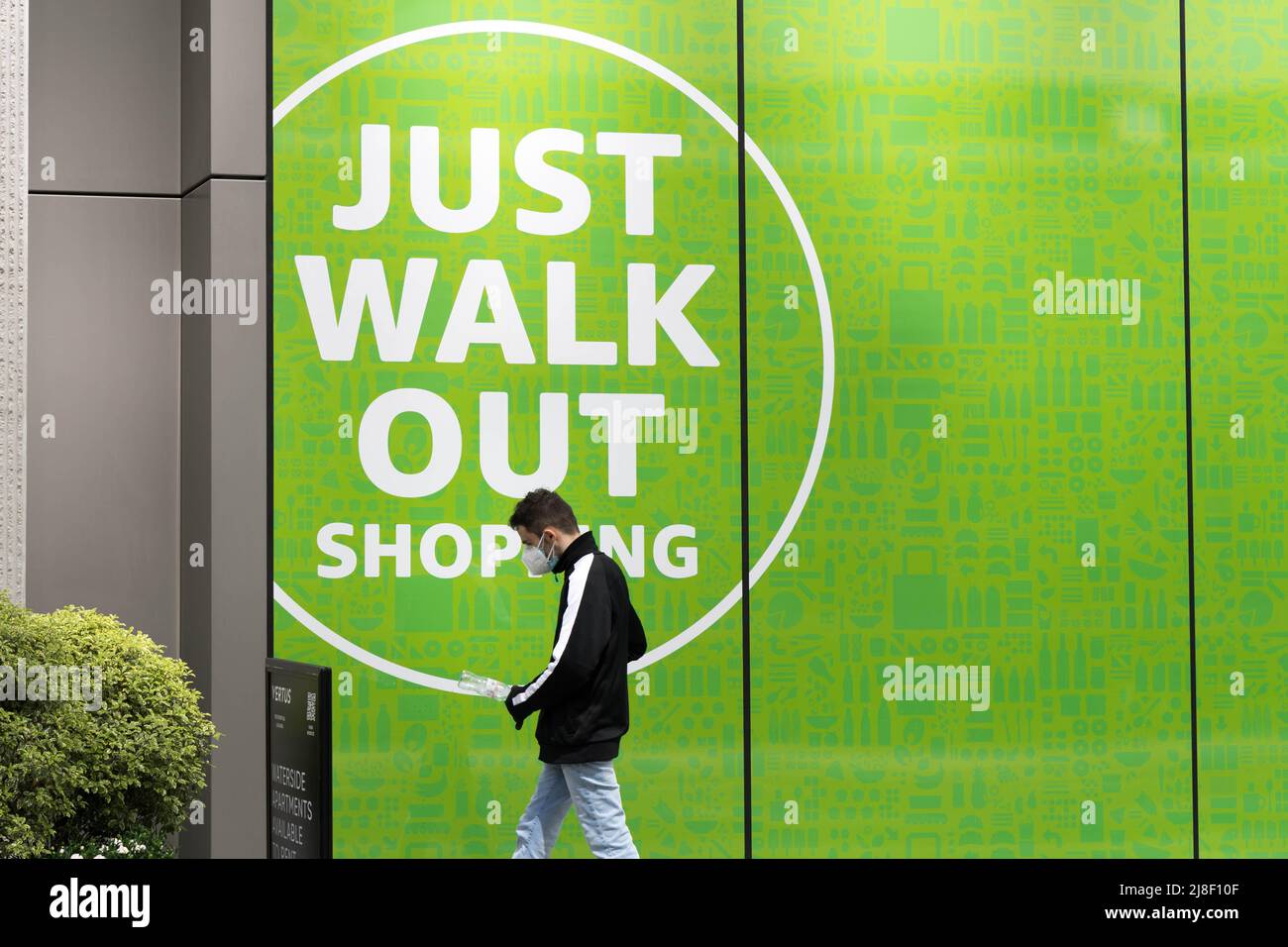 man in face mask shopper outside the amazon grocery shop "amazon just walk out shopping sign" London England UK Stock Photo