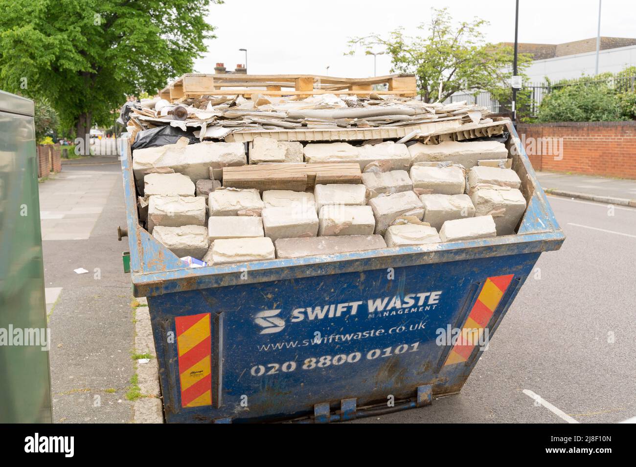 skip loaded with building bricks and rubbles on roadside London England