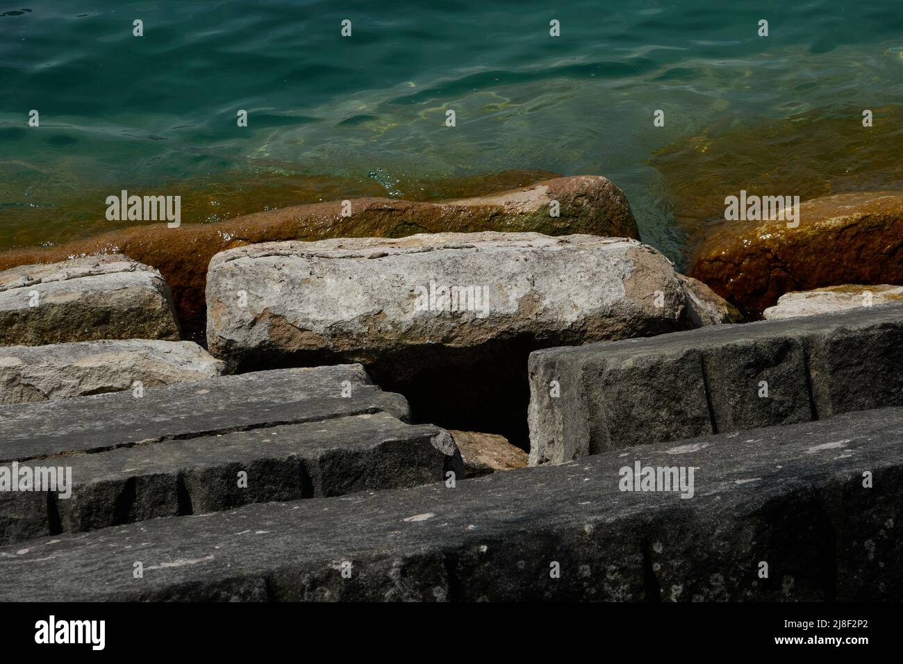 partially submerged rocks with algae along the lakefront Stock Photo