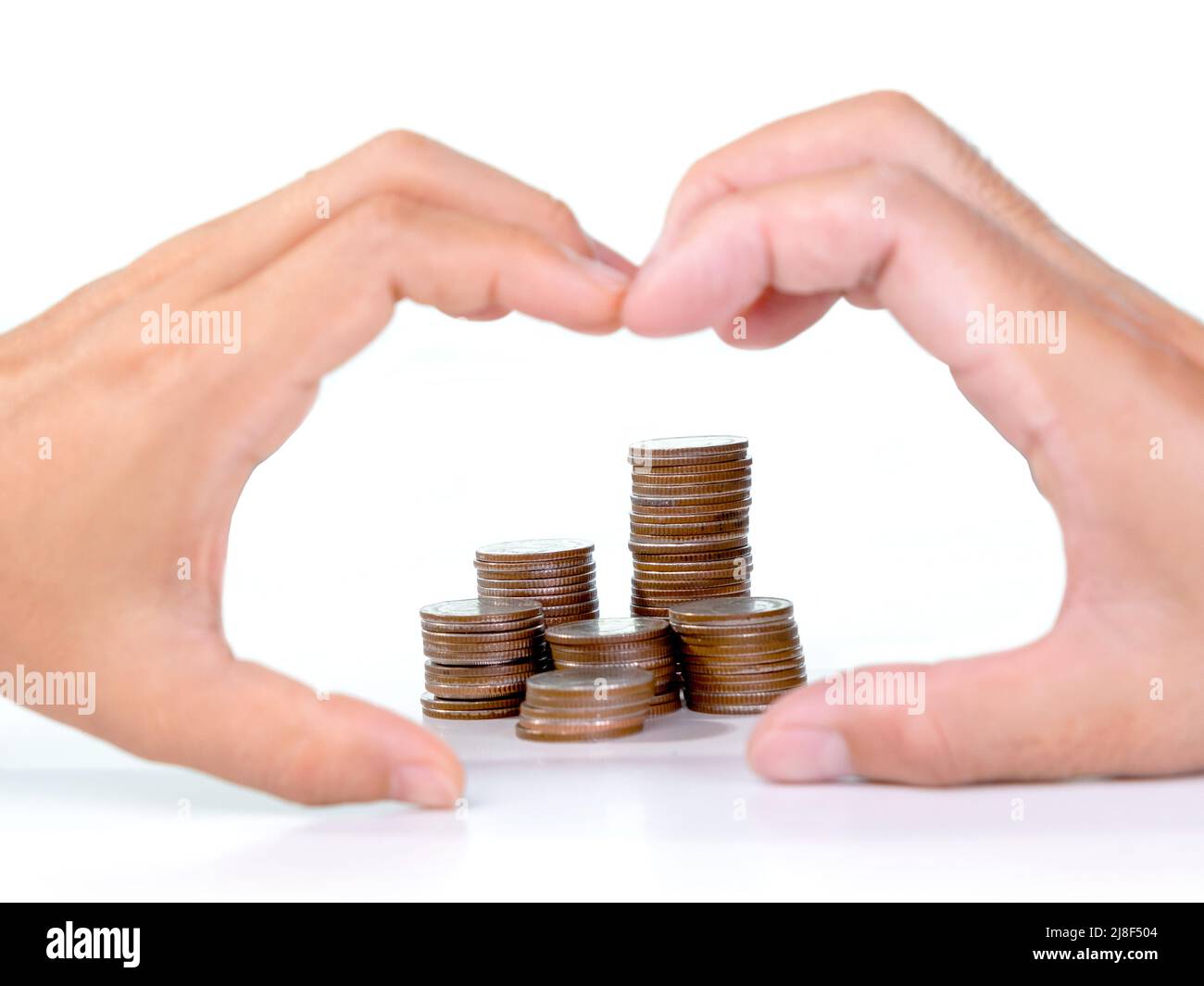 Saving money with stacks of coins for growing your life and couple hands making heart shape on white background. Stock Photo