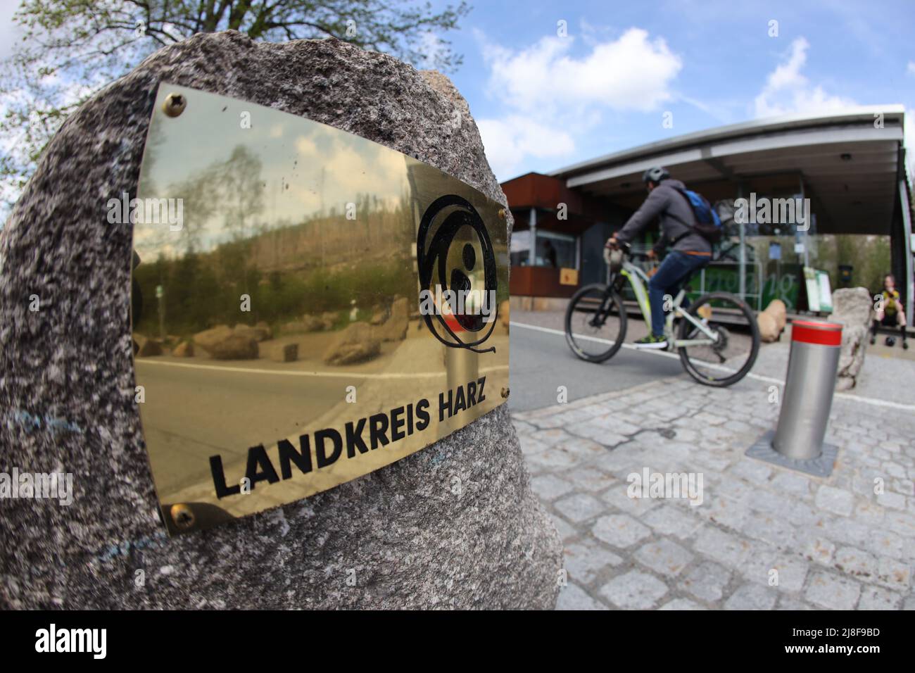 Schierke, Germany. 14th May, 2022. A cyclist sets course for the Brocken. A sign with the inscription 'Landkreis Harz' marks the access road to the Brocken. Due to the persistent drought, there have been several fires in the Harz National Park in recent days. Vast amounts of dead wood lie in the park's forests. Credit: Matthias Bein/dpa/Alamy Live News Stock Photo