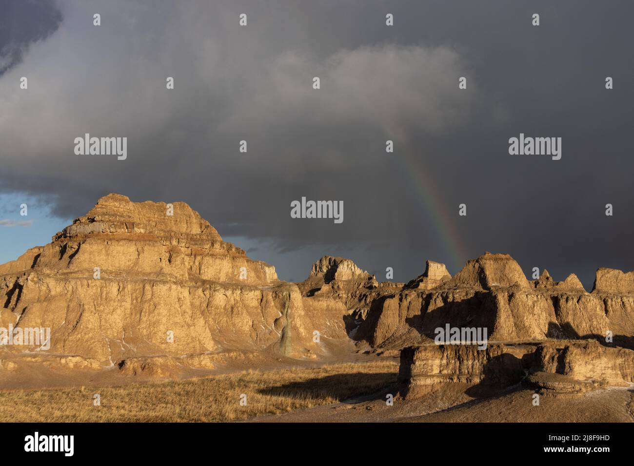 A rainbow is visible behind a rock formation at Badlands National Park