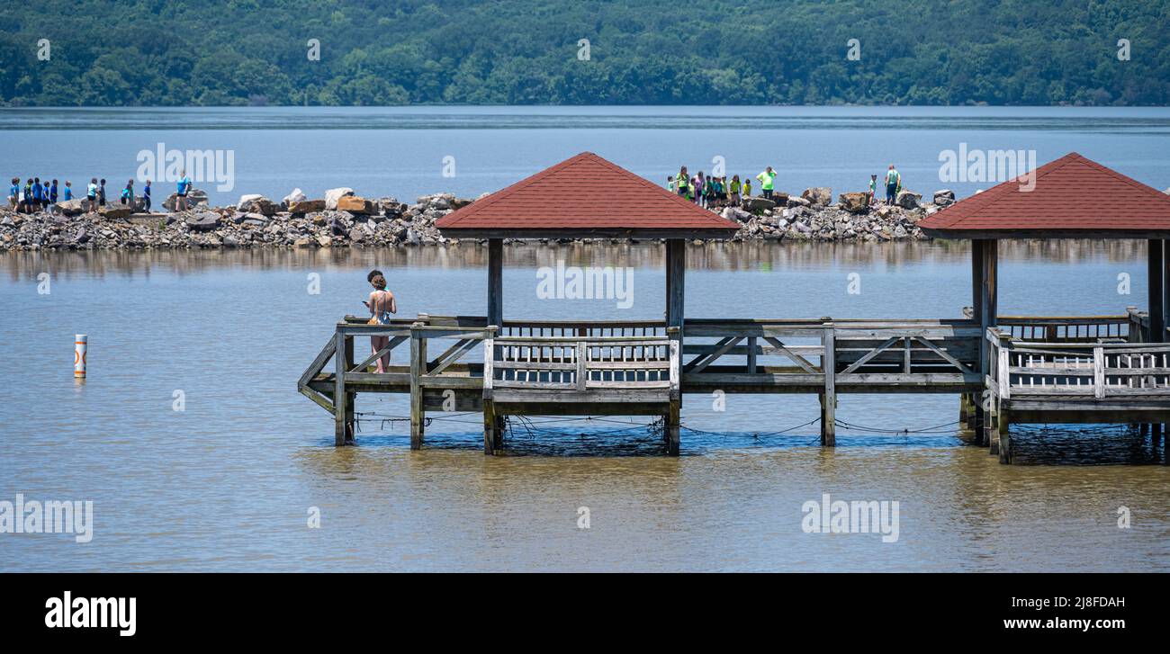 Couple enjoying the view from a fishing pier while school children explore the rock jetty at Lake Dardanelle State Park in Russellville, AR. (USA) Stock Photo