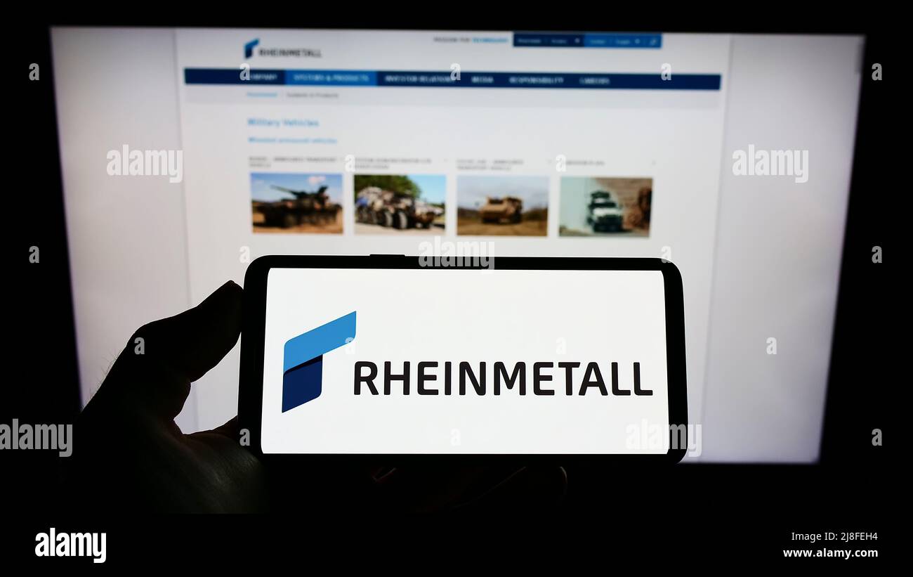 Person holding cellphone with logo of German defence company Rheinmetall AG on screen in front of business webpage. Focus on phone display. Stock Photo