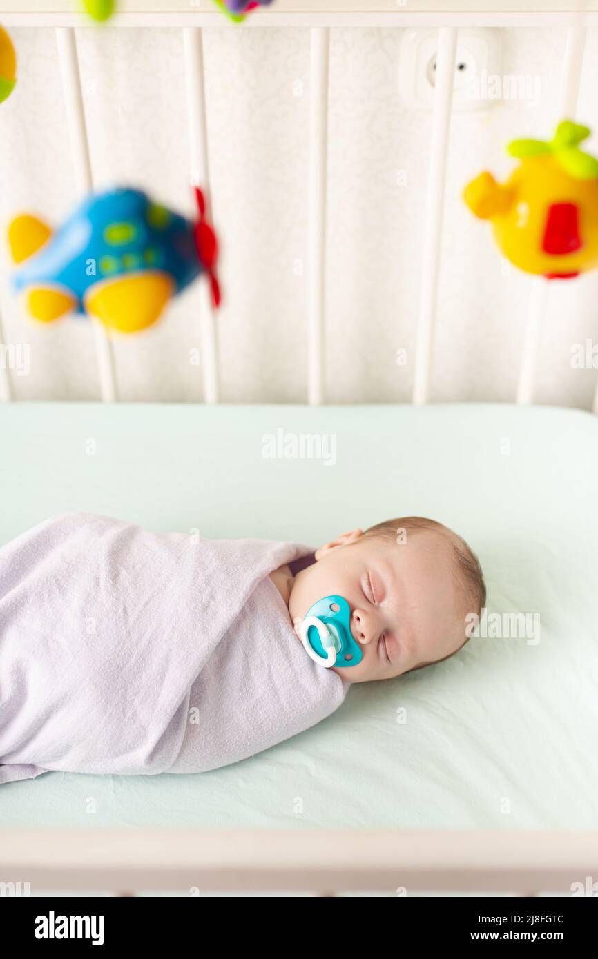 The baby is in the crib . The baby is 03 months old. A calm sleeping