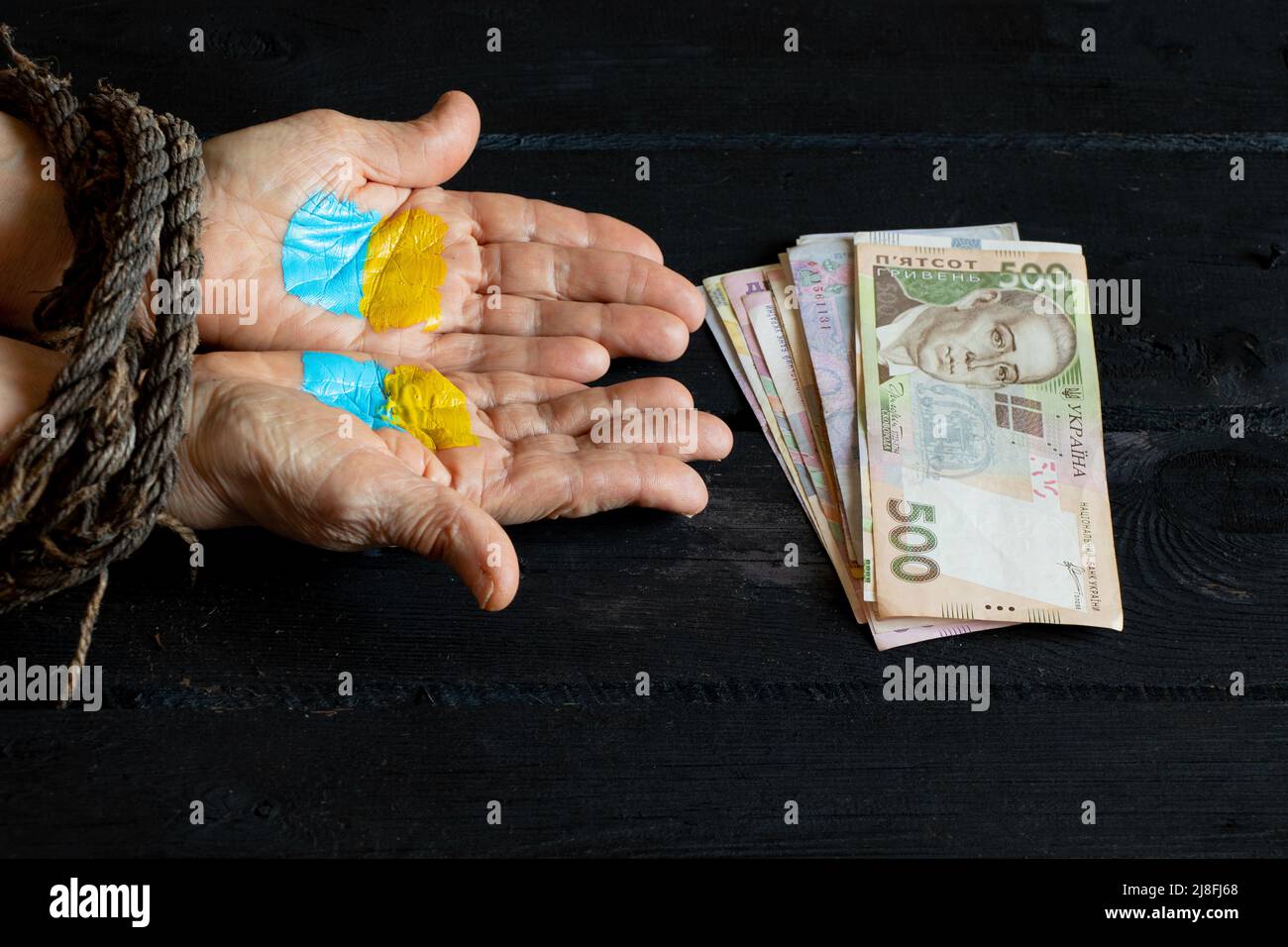 A yellow-blue flag of Ukraine is drawn on the girl's hand and money lies nearby. Martial law in Ukraine 2022. Stop the war. Finance and loans Stock Photo