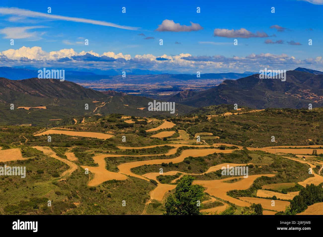 Landscape of terraced fields and mountains surrounding a valley by Iglesia de Santa Maria fortress church in Ujue, Navarra, Spain Stock Photo