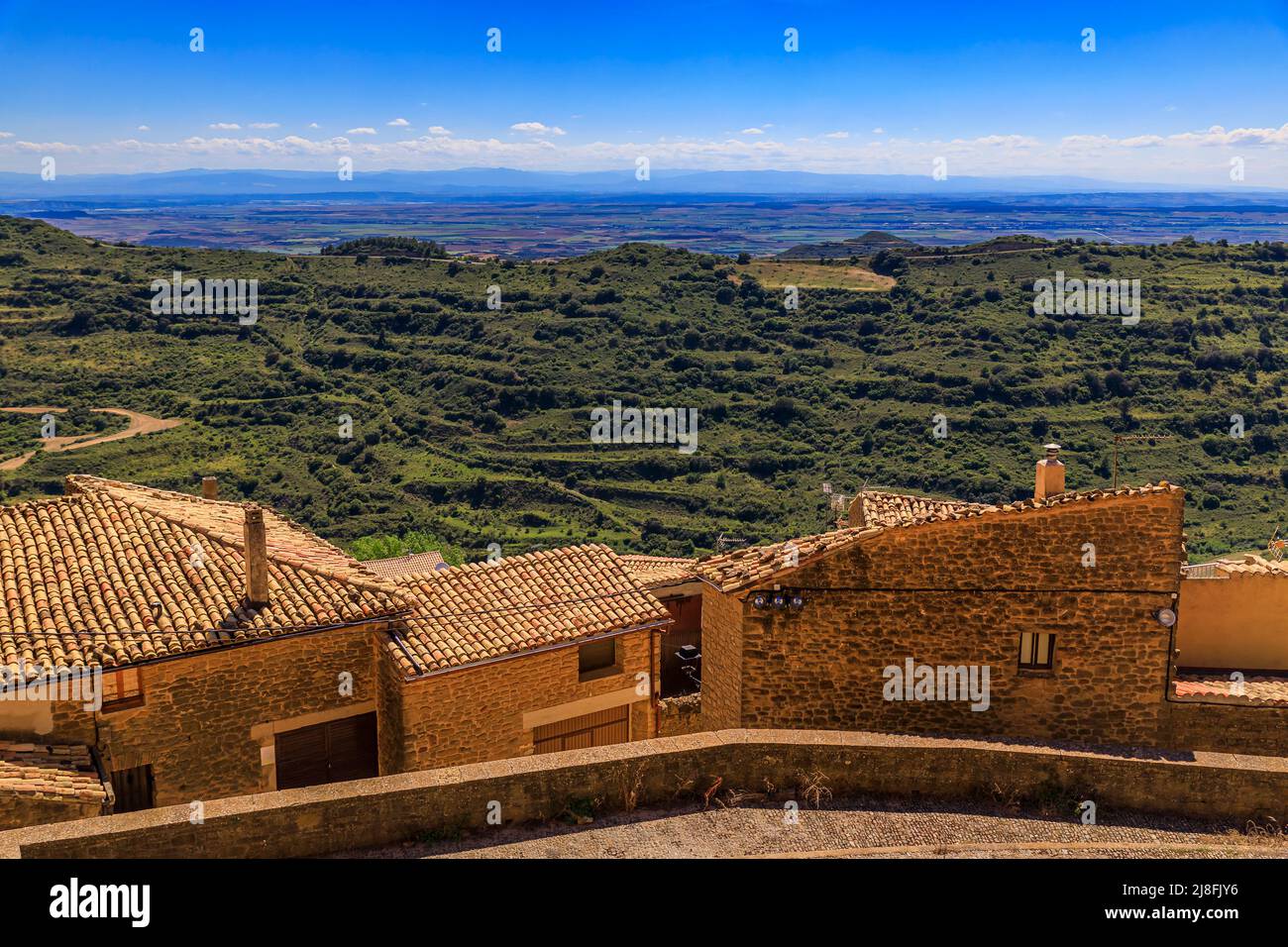 Aerial view of old stone houses and terraced fields surrounding a valley by Iglesia de Santa Maria fortress church in Ujue, Navarra, Spain Stock Photo