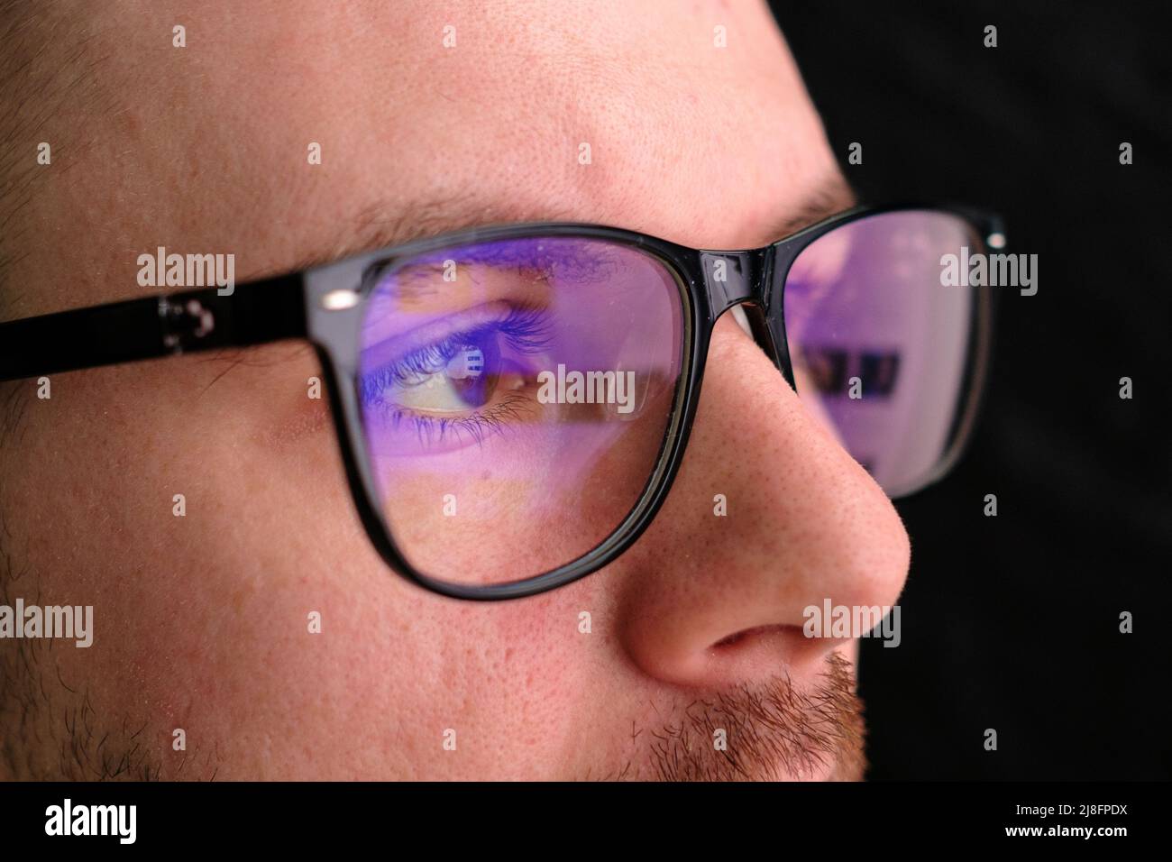 Man in the glasses watches to the monitor. Reflection in the googles. Stock Photo