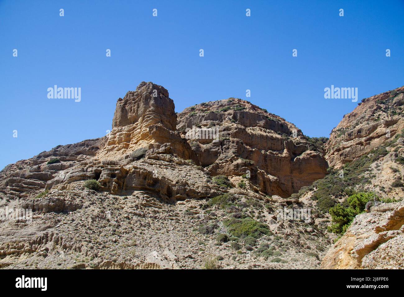 Desolate dry and rough eroded landscape under blue sky Stock Photo