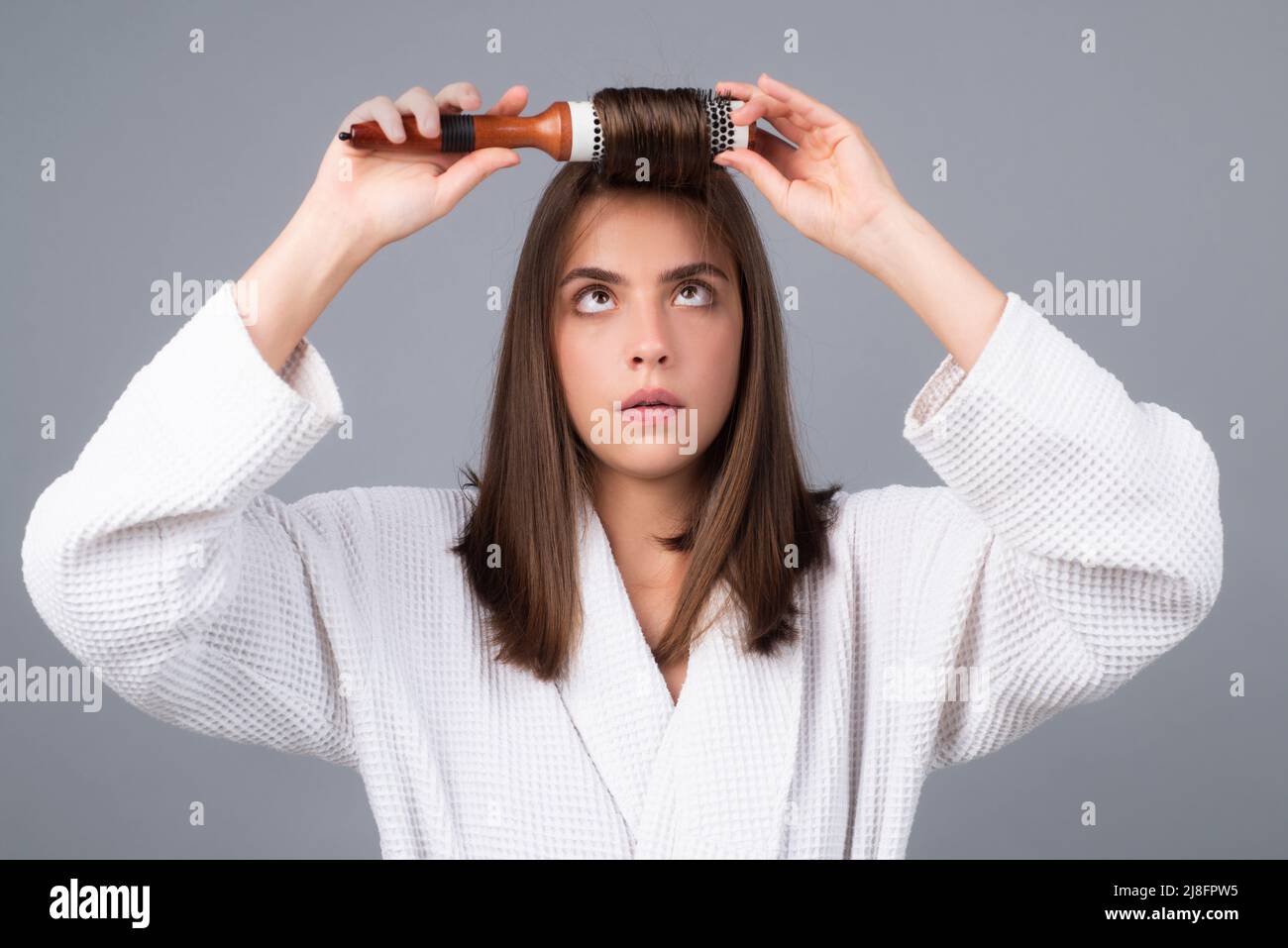 Woman combing hair. Portrait of female model with a comb brushing hair
