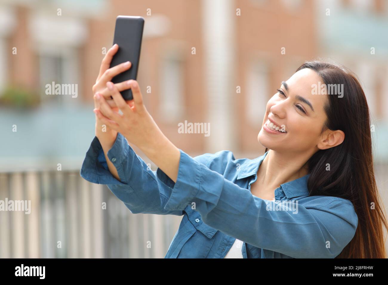 Happy woman posing taking selfie with smart phone in the street Stock Photo