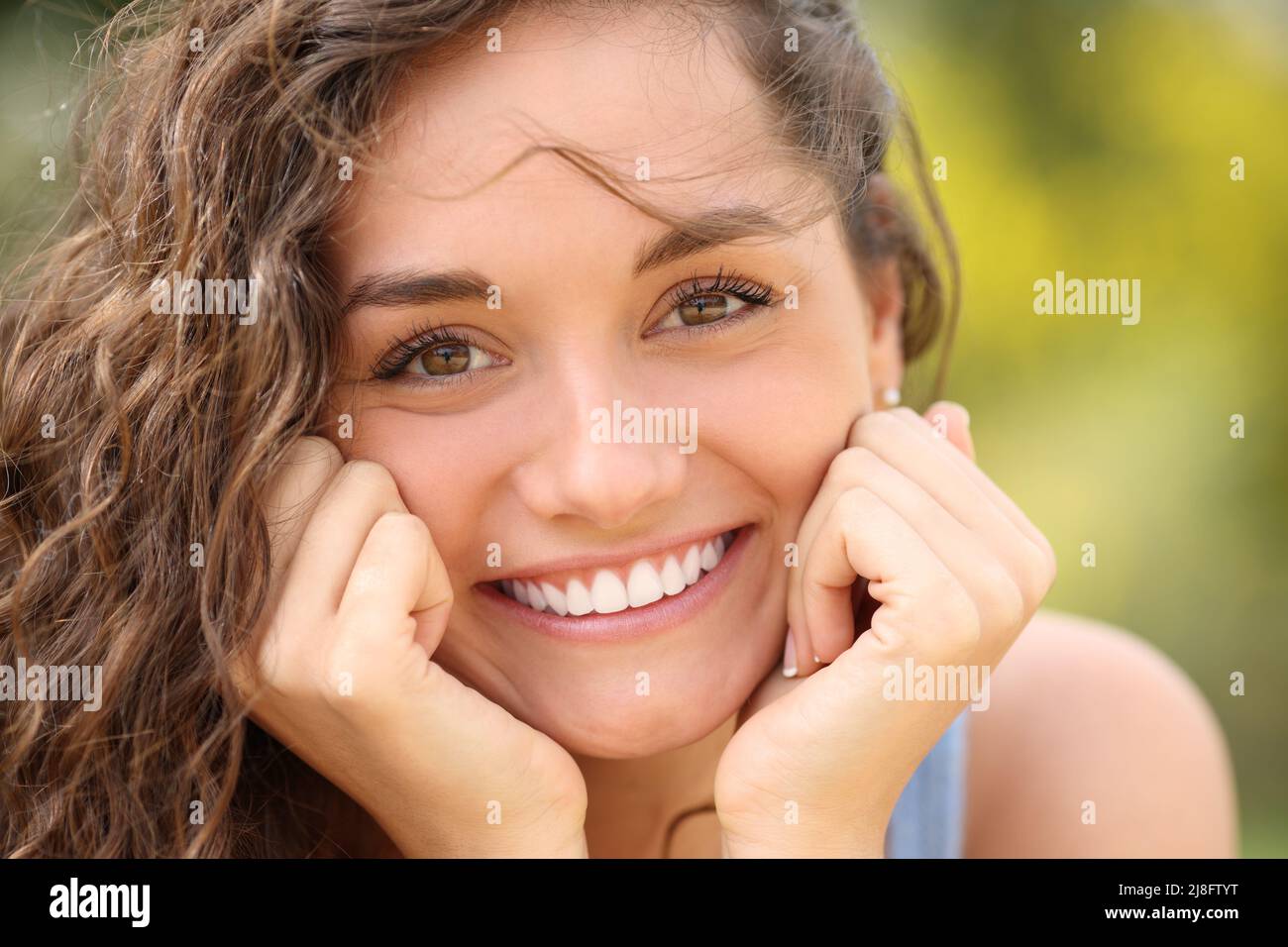 Front view portrait of a beautiful woman with perfect white smile looking at camera in a park Stock Photo