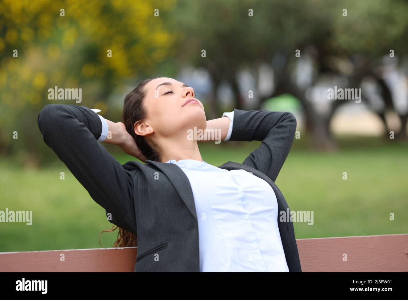 Businesswoman relaxing resting sitting on a bench in a park Stock Photo