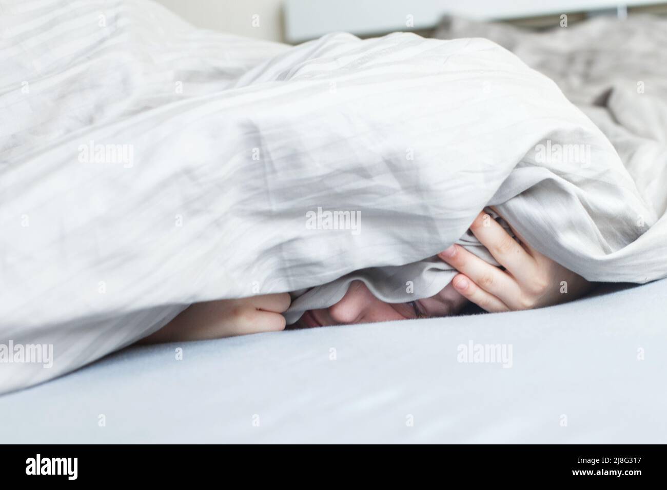 boy in the bed in the morning. the child lies and covers his face with