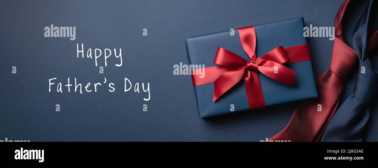 Happy Father's Day banner with blue gift box and neckties on dark blue background. Stock Photo