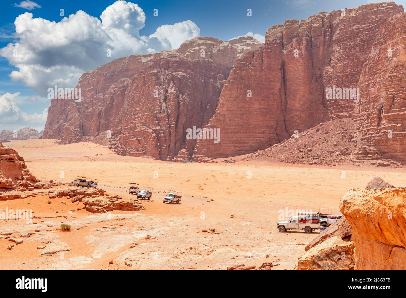 Orange sands and rocks of Wadi Rum desert with bedouin cars in the foreground, Jordan Stock Photo